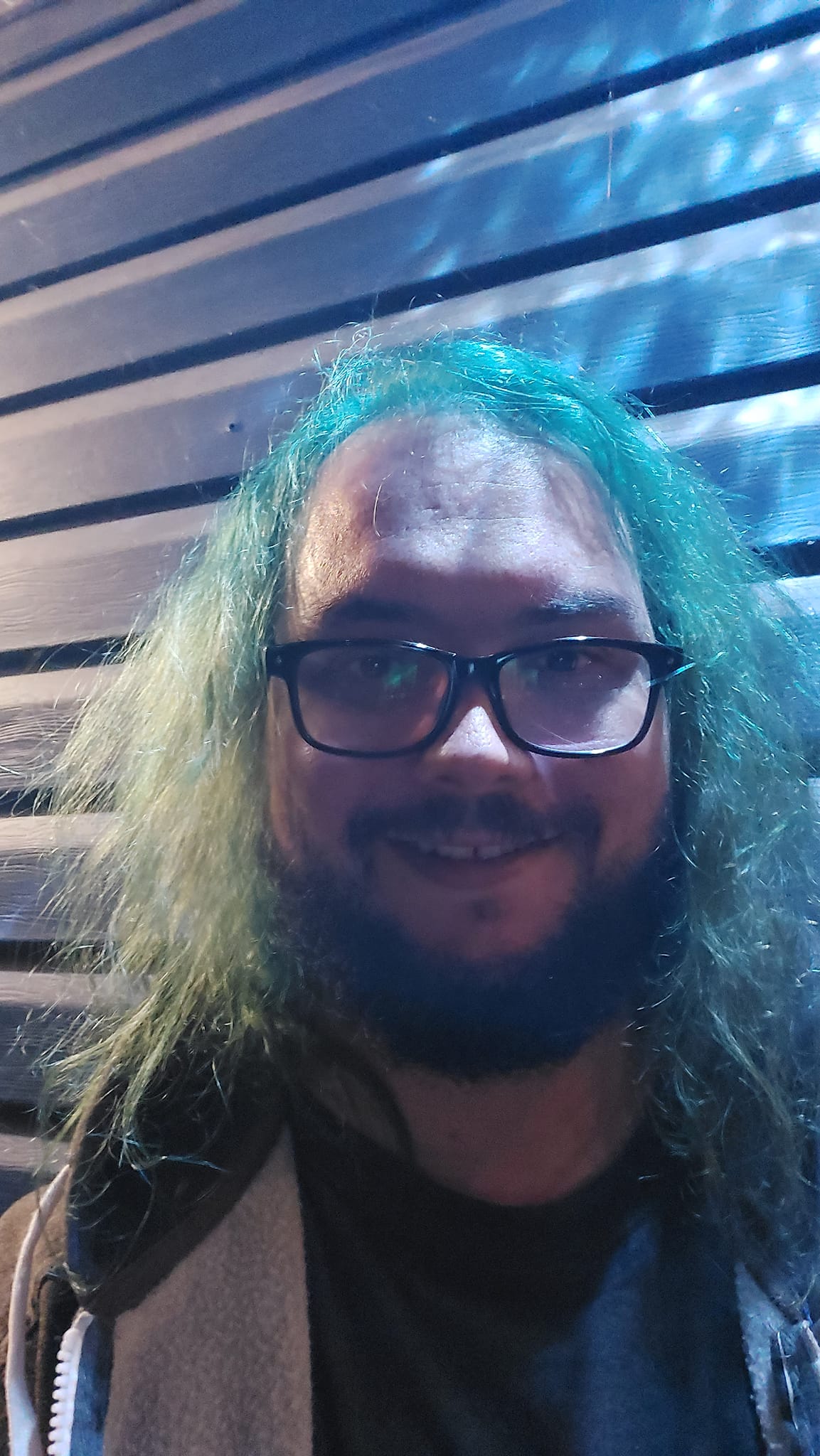 A man with green hair is outside after dark, Photo 3